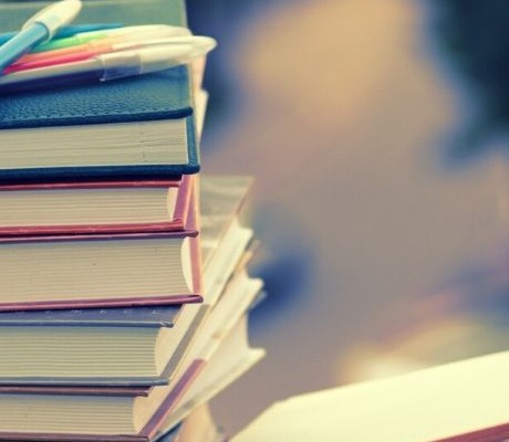 Pile of books and a writing book and pencil
